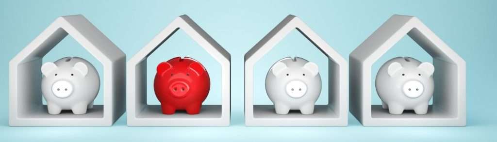 Four piggy banks in houses all white except one which is red
